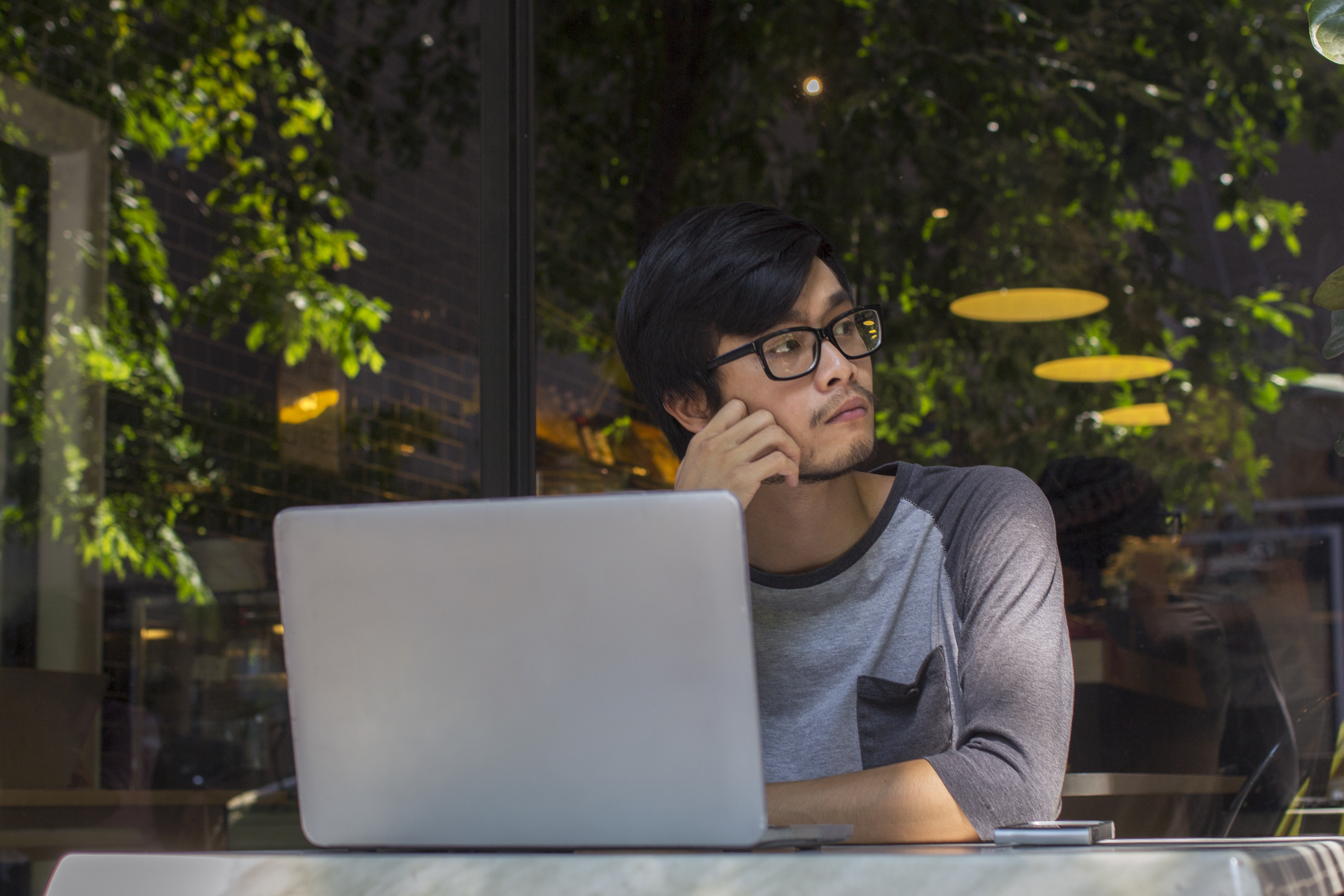 A man sits with his laptop and looks to his left hand side