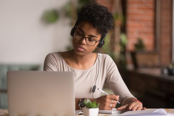 Young student revising on her laptop while listening to music