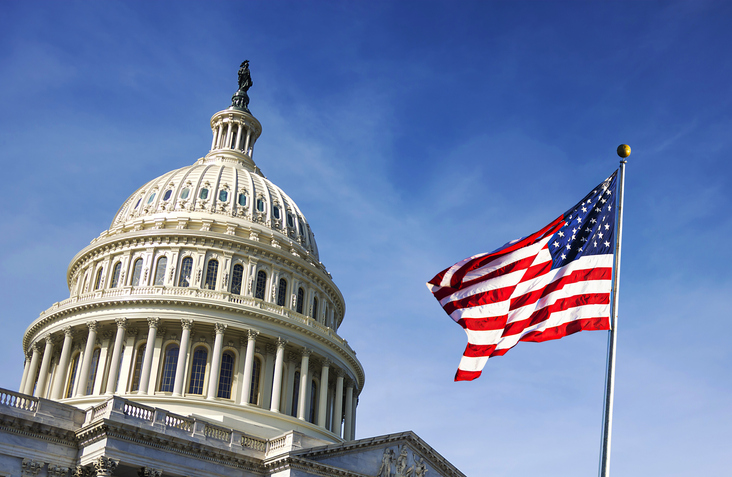 Capitol Hill from below with an American flag billowing outside it