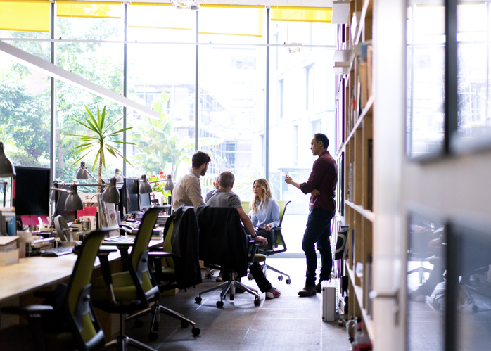 People sit and stand together in a light and airy office space